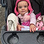 Addisyn is registered to the contest to win money with this photo: baby, toddler, stroller, pink_hat, pom_pom, blanket, blue_eyes, face, hand, paper, cup_holder, stroller_seat, outdoor, gravel, winter_clothing, jacket, dirt_smudge, rosy_cheeks, sitting, portrait