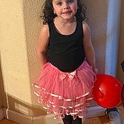 Harlee is registered to the contest to win money with this photo: child, girl, tutu, pink_bow, red_balloon, curly_hair, smile, earrings, black_top, pink_skirt, bare_feet, hardwood_floor, indoor, wall, portrait, posing, playful, party, home_interior, young_child