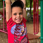 Jesse joined the competition — help win amazing prizes! child, boy, smiling, playground, red_shirt, baseball_cap, monkey_bars, park, outdoor, trees, wood_chips, face, teeth, arms_up, casual_clothing, play, batman, happy, portrait, depth_of_field