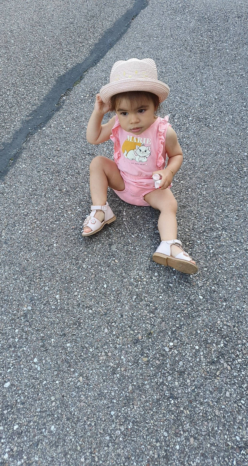 Thaïs a rejoint le concours — aidez-le/la à gagner de superbes lots ! asphalt, baby, baby_toddler_clothing, cap, child, foot, fun, grass, hat, human_leg, people_in_nature, person, recreation, road, road_surface, sidewalk, sitting, soil, sun_hat, tar