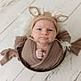 baby, infant, knit_hat, deer_ears, brown_wrap, basket, wooden_floor, cozy, cute, portrait, indoors, child, newborn, wrapped, soft_texture, face, expression, small_hands, headwear, flooring