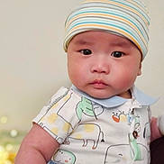 Alex is registered to the contest to win money with this photo: baby, child, infant, face, beanie, hat, clothing, onesie, animal_print, cute, portrait, skin, cheeks, eyes, person, indoor, closeup, expression, headwear, young