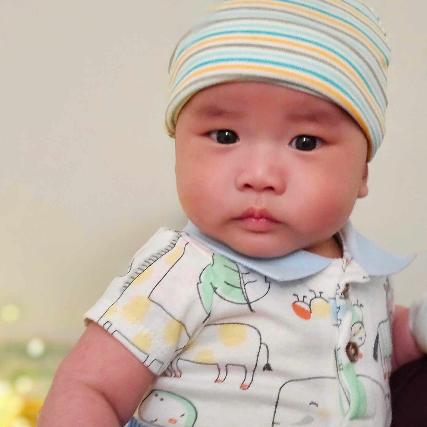 Alex is registered to the contest to win money with this photo: baby, child, infant, face, beanie, hat, clothing, onesie, animal_print, cute, portrait, skin, cheeks, eyes, person, indoor, closeup, expression, headwear, young