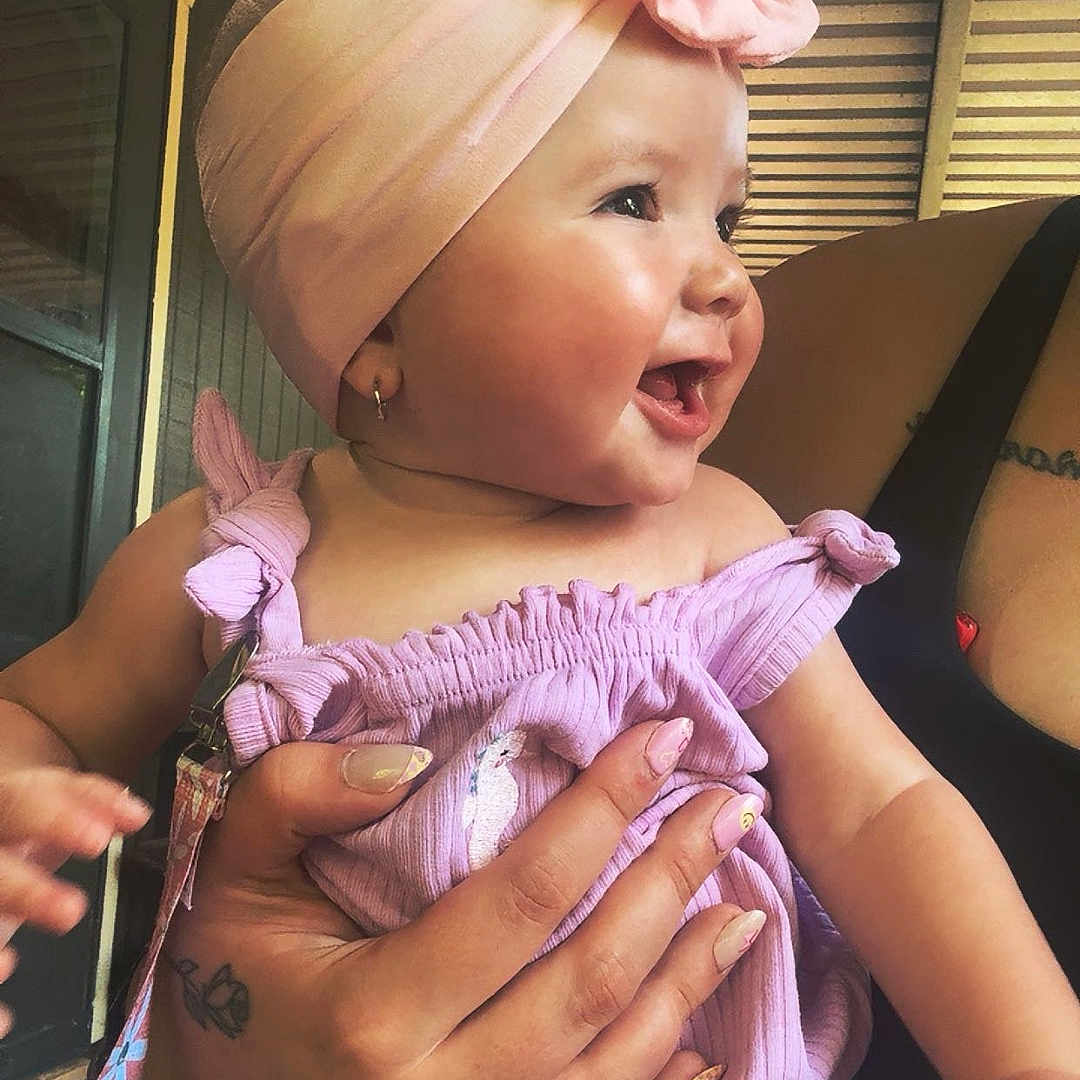 Renesmae joined the competition — help win amazing prizes! arm, baby, child, cute, face, hand, happy, holding, indoor, nail_polish, person, pink_headband, pink_outfit, portrait, ring, skin, smiling, tattoo, woman, young_child