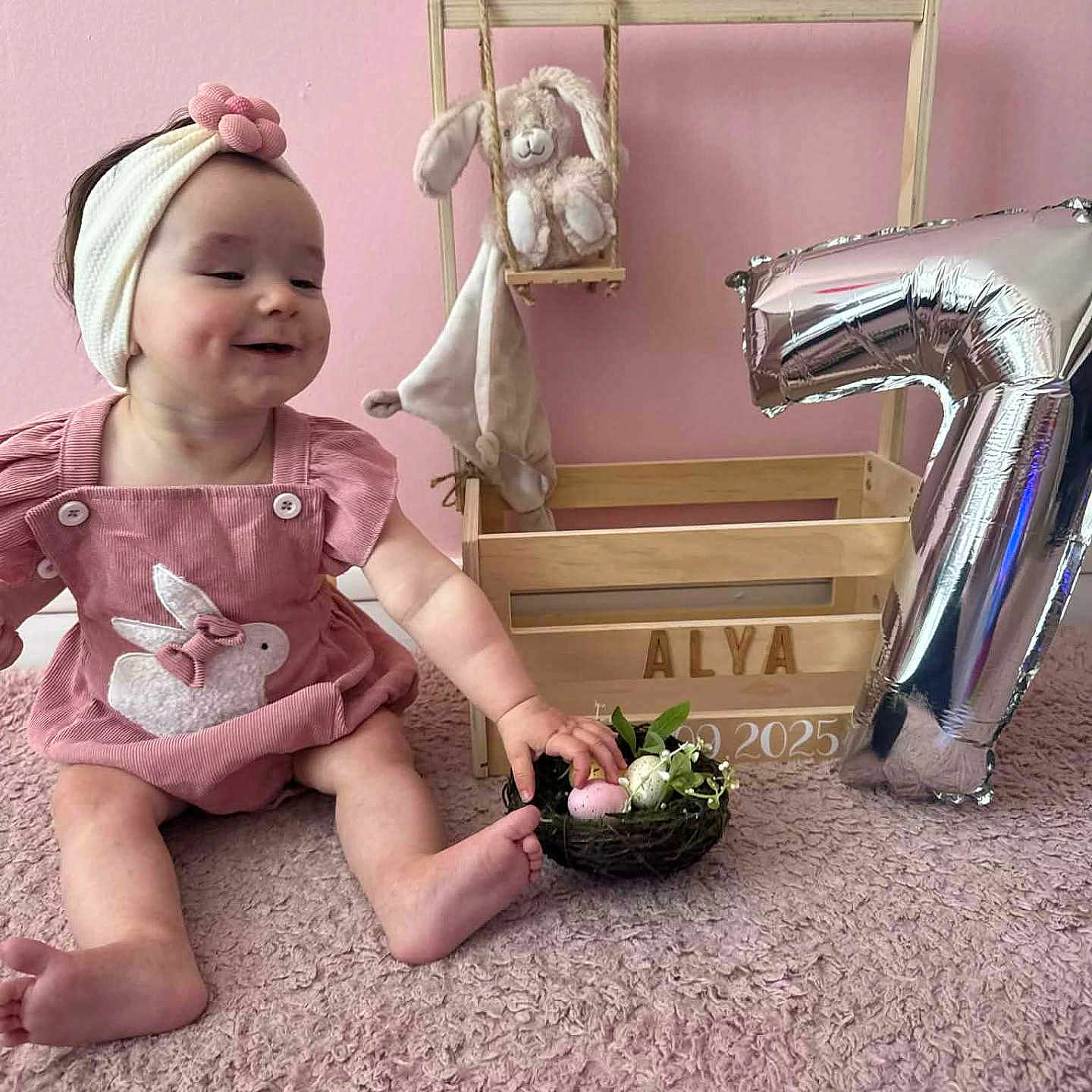 Alya a rejoint le concours — aidez-le/la à gagner de superbes lots ! baby, child, pink, carpet, headband, bunny, toy, stuffed_animal, crate, balloon, number, celebration, smiling, cute, indoor, person, decor, nest, eggs, happy