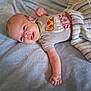 baby, infant, smiling, onesie, pizza, blanket, striped_cloth, drool, lying_down, happy, cute, child, soft_texture, indoors, young, person, face, small_hand, apparel, relaxing