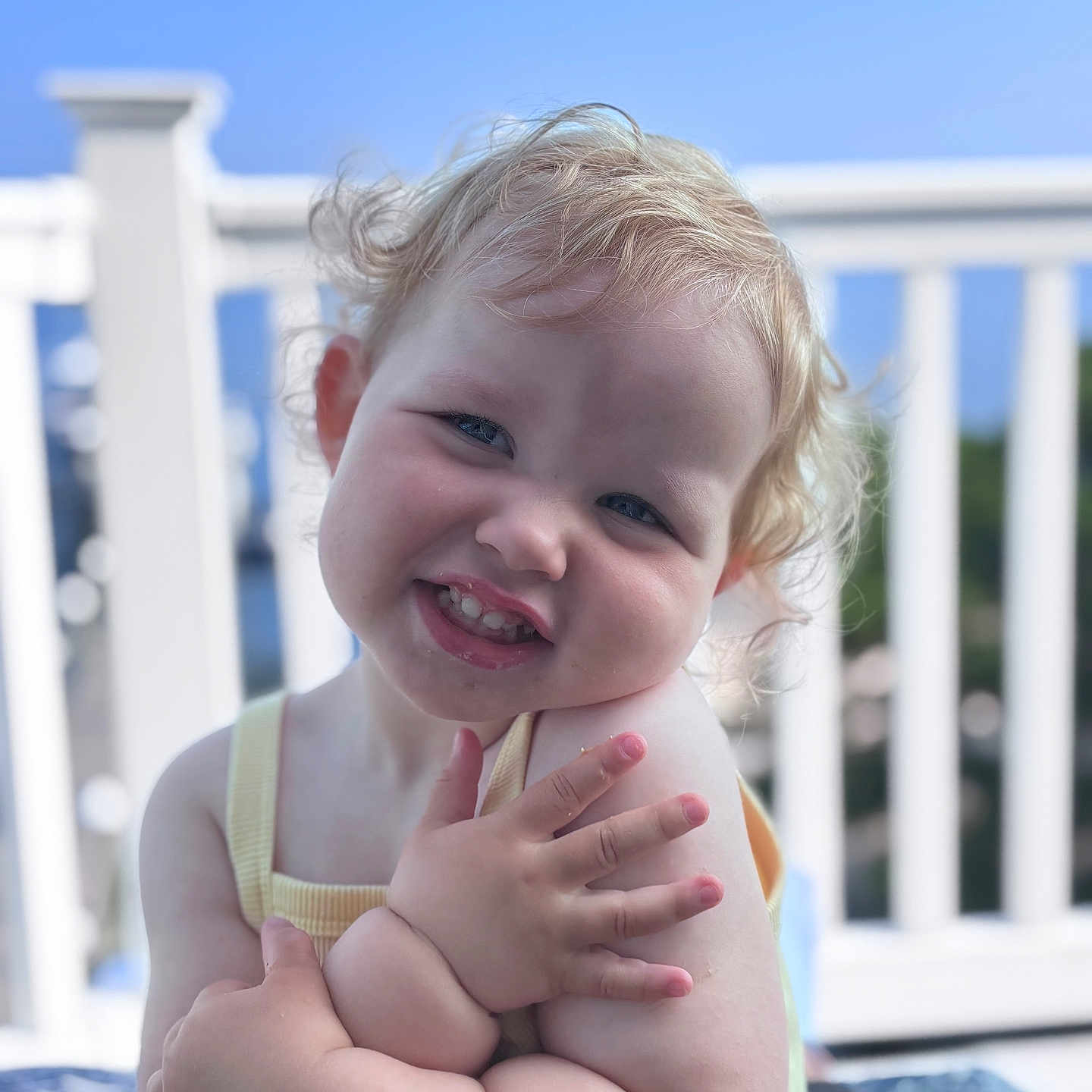 Penelope joined the competition — help win amazing prizes! toddler, child, smile, curly_hair, blond, outdoor, sunlight, railing, blue_sky, portrait, happy, cute, skin, face, arms, sleeveless, person, baby, expression, daylight