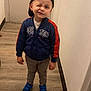 Naël a rejoint le concours — aidez-le/la à gagner de superbes lots ! child, boy, winking, cap, jacket, blue_shoes, pants, standing, indoor, hallway, wooden_floor, door, wall, casual_clothing, smile, footwear, person, young, cute, playful