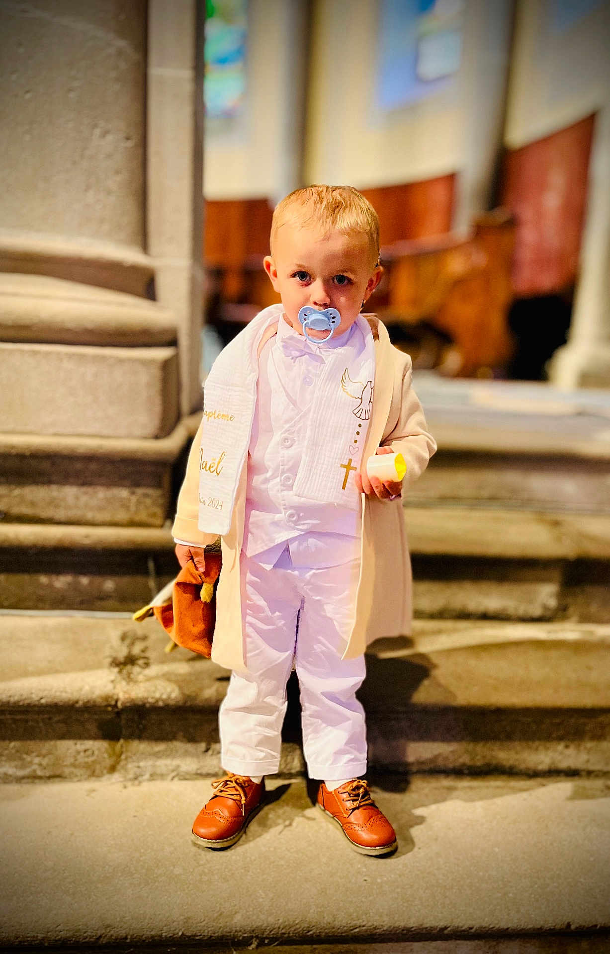 Naël participe au concours pour gagner de l'argent avec cette photo : child, toddler, pacifier, white_clothing, beige_coat, brown_shoes, toy, stairs, indoor, portrait, blond_hair, serious_expression, holding_object, steps, stone, formal_wear, cute, person, baby, small