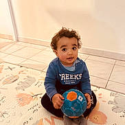Jackson a rejoint le concours — aidez-le/la à gagner de superbes lots ! ball, blue_sweater, casual_clothing, child, curious, curly_hair, cute, floor_mat, home, indoor, looking_up, person, play, play_mat, sitting, smiling, tile_floor, toddler, toy, young_child