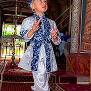 Annaser a rejoint le concours — aidez-le/la à gagner de superbes lots ! child, boy, traditional_clothing, blue, white, hat, peace_sign, carpet, indoors, decorative, pattern, portrait, smiling, person, fashion, cultural, shoes, standing, expression, celebration