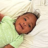 baby, infant, child, lying_down, green_onesie, polka_dot, blanket, play_mat, elephant_pattern, geometric_shapes, happy, smiling, indoors, cozy, soft_fabric, cute, portrait, young_child, comfortable, relaxed