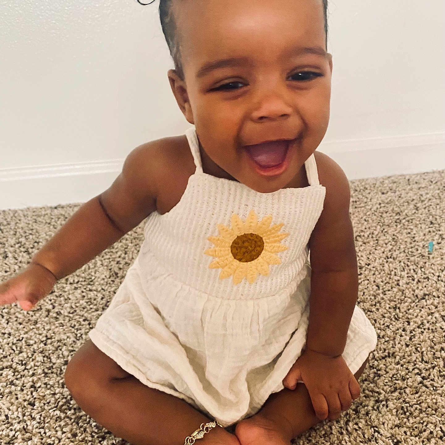Reason is registered to the contest to win money with this photo: anklet, arm, baby, carpet, child, cute, floor, hair_bows, hands, happy, indoors, laughing, portrait, sitting, skin_tone, smiling, sunflower_dress, toddler, toes, wall