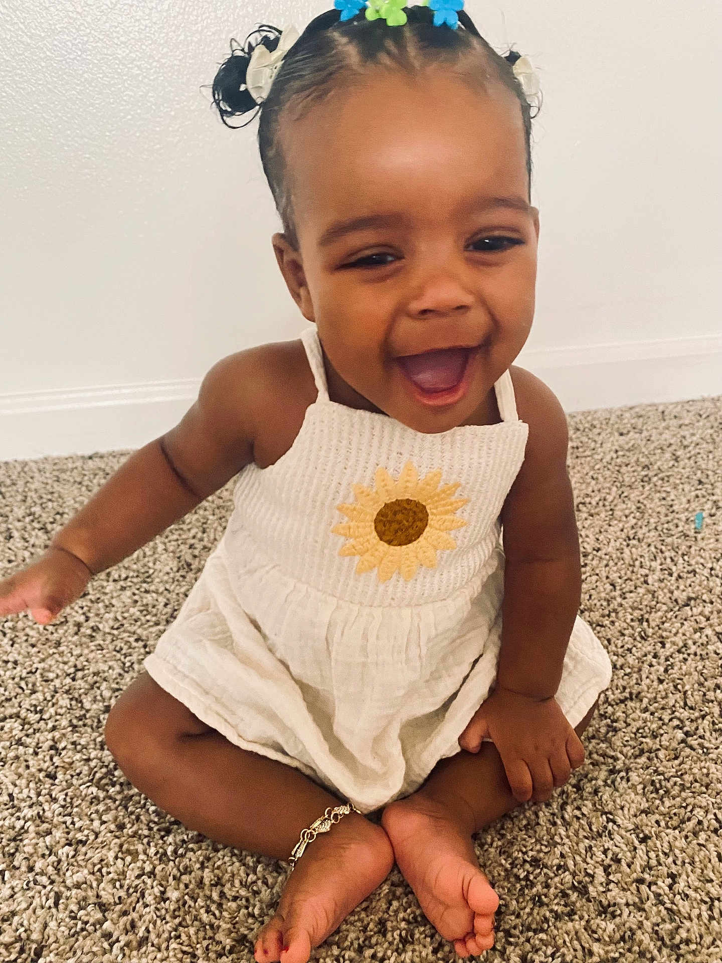Reason is registered to the contest to win money with this photo: child, toddler, baby, smiling, sunflower_dress, sitting, carpet, anklet, hair_bows, happy, indoors, portrait, toes, cute, skin_tone, laughing, floor, wall, arm, hands