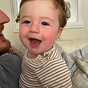 Wilfred joined the competition — help win amazing prizes! child, toddler, smiling, indoor, person, curly_hair, striped_clothing, adult, face, happy, couch, pillow, cozy, portrait, closeup, family, home, cute, infant, joy