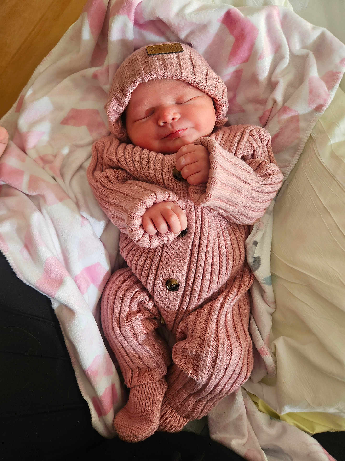 Sophie is registered to the contest to win money with this photo: baby, newborn, infant, pink, blanket, hat, knitwear, onesie, sleeping, smiling, hand, fingers, button, bed, bedding, cozy, portrait, cute, indoors, soft