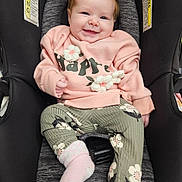 Sophie joined the competition — help win amazing prizes! baby, infant, child, car_seat, smiling, pink_sweater, floral_pants, socks, seat_harness, warning_label, cute, portrait, close_up, hair, cheeks, hands, fabric, upholstery, happy, indoor