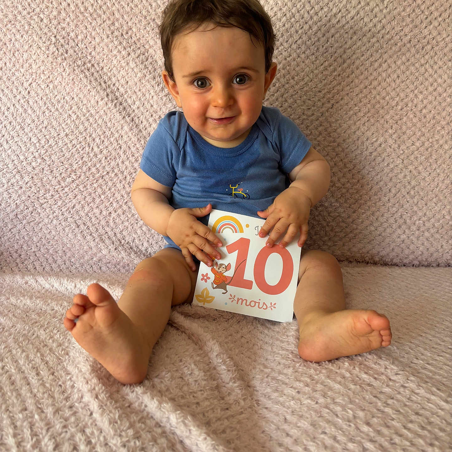 Eneko participe au concours pour gagner de l'argent avec cette photo : baby, barefoot, blanket, blue_onesie, child, cute, expression, face, feet, hands, happy, indoors, infant, milestone_card, person, portrait, sitting, skin, smiling, young