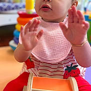 Alana joined the competition — help win amazing prizes! toddler, child, girl, portrait, sitting, playroom, toy, colorful, strawberry, pink, red, striped_shirt, hair_bows, curly_hair, hands_up, curious, looking_up, indoor, wooden_toy, smiling