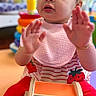 toddler, child, girl, portrait, sitting, playroom, toy, colorful, strawberry, pink, red, striped_shirt, hair_bows, curly_hair, hands_up, curious, looking_up, indoor, wooden_toy, smiling