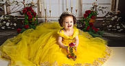 Alana is registered to the contest to win money with this photo: child, toddler, baby, portrait, smiling, happy, tiara, princess, yellow_dress, gown, formalwear, roses, flowers, candles, garden, gift, decorated_object, seated, studio_photography, royal_theme
