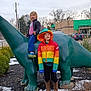 Jason joined the competition — help win amazing prizes! bushes, car, child, cowboy_boots, dinosaur_statue, funny_face, gas_station, kids, outdoor, playful, rainbow_jacket, sculpture, sidewalk, sky, snow, statue, street, toy, trees, winter