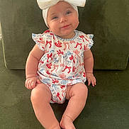 Ella is registered to the contest to win money with this photo: baby, child, infant, bow, headband, dress, pattern, sitting, couch, green, smile, cute, happy, indoors, furniture, person, skin, legs, feet, portrait