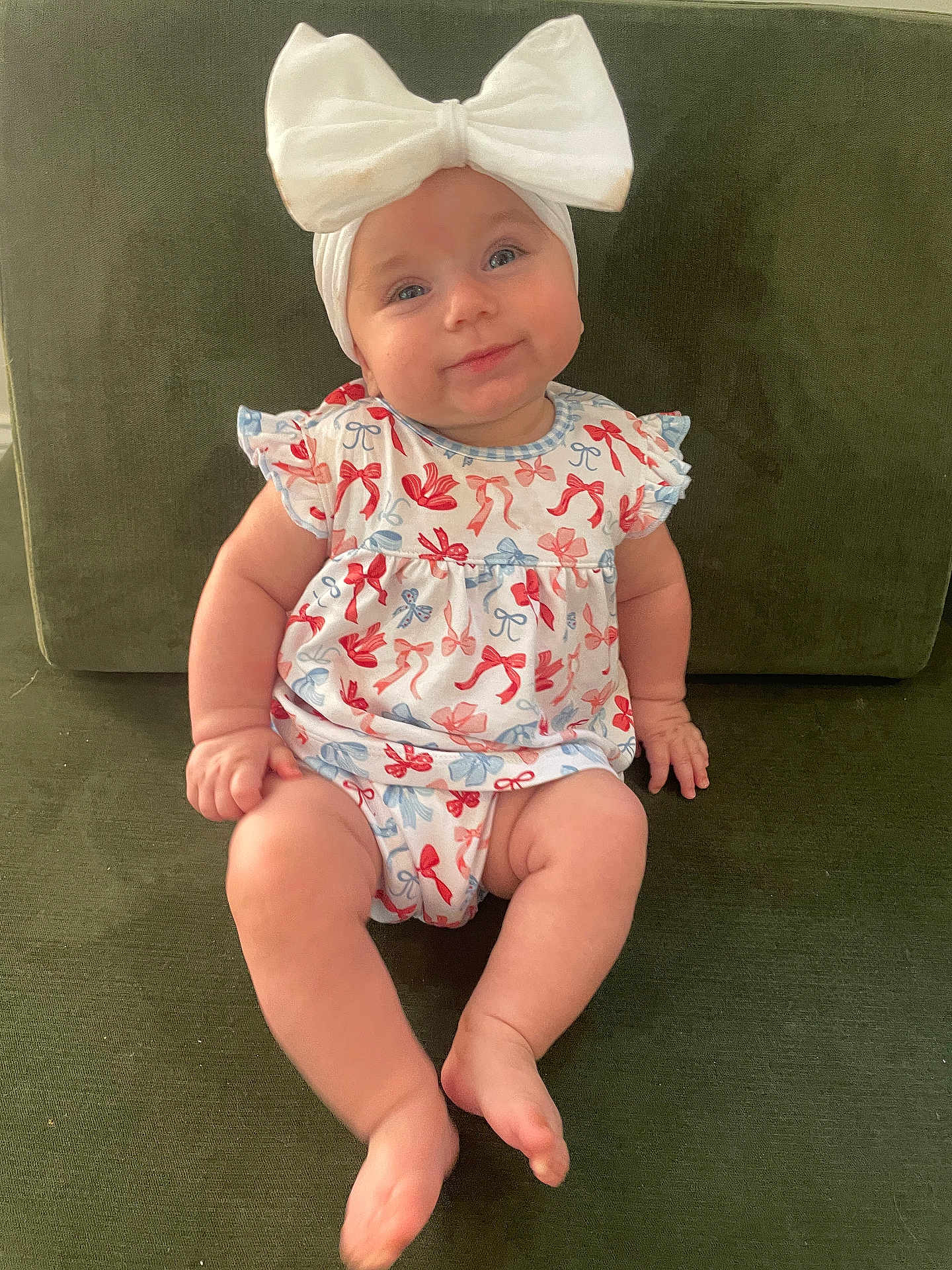 Ella is registered to the contest to win money with this photo: baby, child, infant, bow, headband, dress, pattern, sitting, couch, green, smile, cute, happy, indoors, furniture, person, skin, legs, feet, portrait