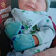 Lewis joined the competition — help win amazing prizes! baby, bib, child, closeup, clothing, cozy, cute, hand, happy, hat, holding, indoor, infant, mittens, onesie, person, portrait, smiling, soft, warm