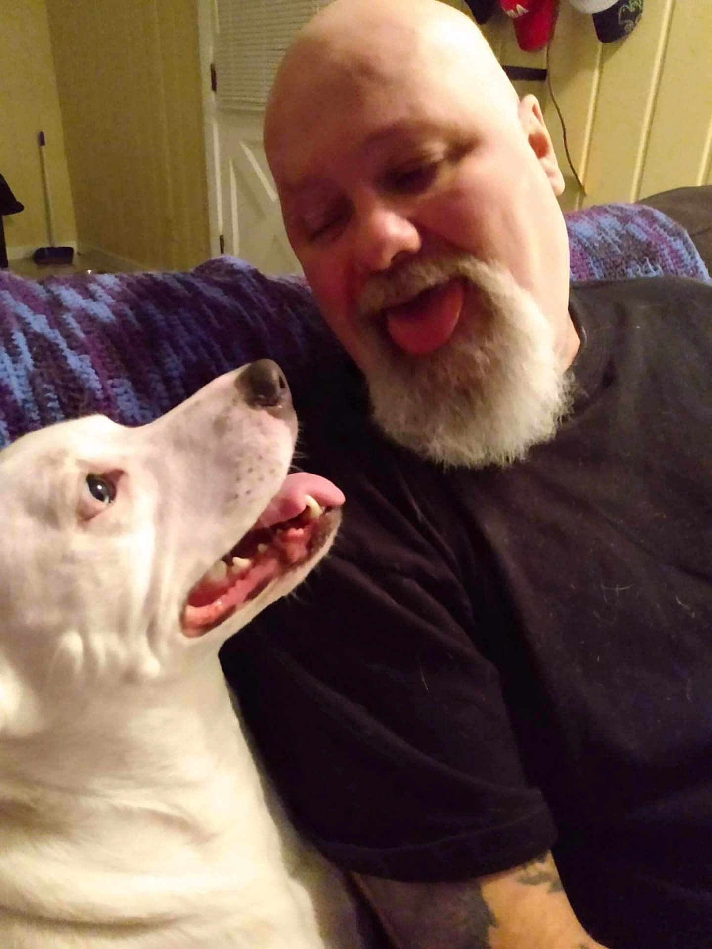 Buckwheat joined the competition — help win amazing prizes! man, dog, white_dog, beard, bald, tongue_out, smiling, indoor, couch, purple_blanket, tattoo, black_shirt, pet, happy, face, closeup, friendship, funny, playful, companion