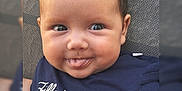 Lolie participe au concours pour gagner de l'argent avec cette photo : baby, child, face, smile, tongue_out, blue_shirt, text_on_clothing, heart_symbol, closeup, portrait, cute, happy, infant, person, skin, head, eyes, hair, sitting, indoors