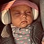 baby, sleeping, headphones, pink_headband, polka_dot_pajamas, closeup, child, infant, soft_lighting, cozy, peaceful, portrait, cute, resting, indoors, clothing, face, person, babywearing, comfort