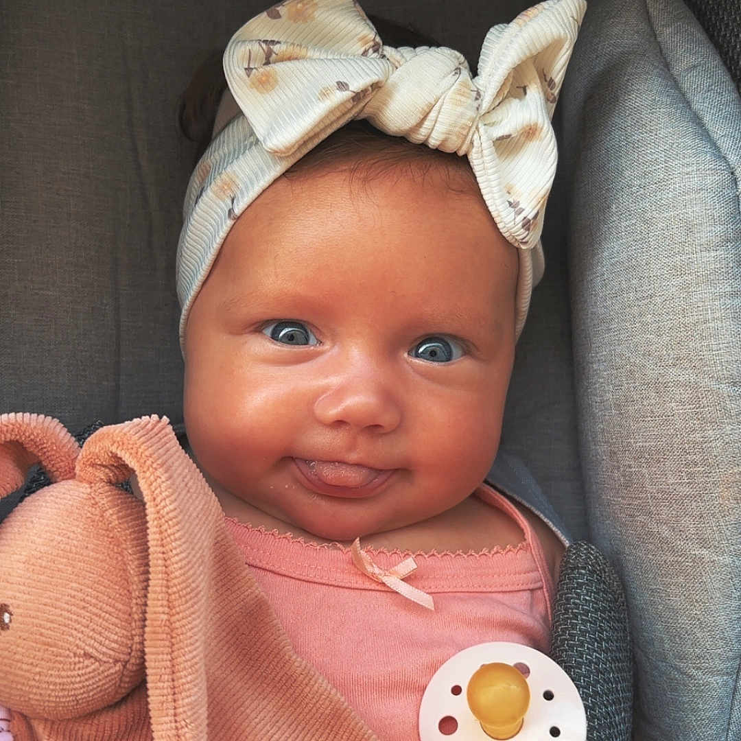 Lolie a rejoint le concours — aidez-le/la à gagner de superbes lots ! baby, blue_eyes, bow_headband, bunny, child, close_up, cushioned_seat, cute, happy, headwear, indoors, infant, pacifier, pink_clothing, plush_toy, portrait, skin, smiling, soft_texture, tongue_out