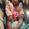 baby, child, car_seat, pink_jacket, checkered_outfit, pacifier, toy, captain_america, smiling, happy, infant, sitting, car_interior, seatbelt, footwear, clothing, cute, portrait, indoors, person