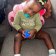 Anria is registered to the contest to win money with this photo: toddler, child, pacifier, toy_ball, couch, socks, hair_clips, green_shirt, plush_toy, cushion, indoor, cute, sitting, portrait, relaxed, smiling, young_child, baby, happy, cozy