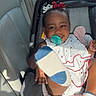 baby, child, car_seat, pacifier, smiling, white_dress, red_bow, socks, foot, car_interior, window, sunlight, happy, infant, seat_belt, cute, portrait, playful, young_child, seat