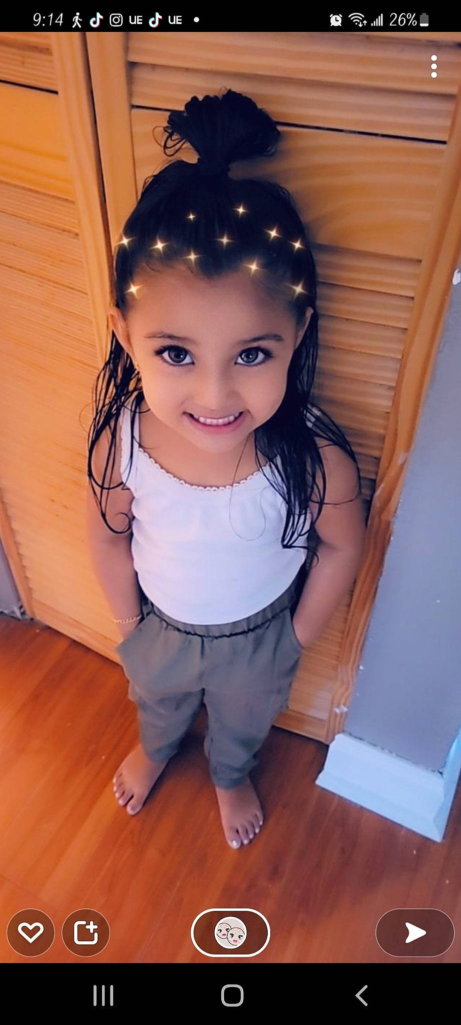 Gia is registered to the contest to win money with this photo: baby_toddler_clothing, black_hair, clothing, eyebrow, eyelash, eyewear, flooring, fun, happy, hardwood, headpiece, joy, lip, neck, person, skin, smile, t_shirt, toy, waist