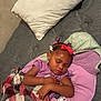 Ahlani is registered to the contest to win money with this photo: bed, blanket, child, clothing, comfort, cute, face, hair_bows, indoor, jacket, nap, peaceful, person, pillow, plaid, purple, relaxation, rest, sleeping, toddler