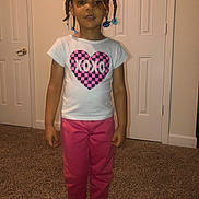 Maryana is registered to the contest to win money with this photo: child, girl, standing, indoor, carpet, tshirt, pants, barefoot, braids, beads, door, white, pink, heart, xoxo, clothing, person, portrait, home, young
