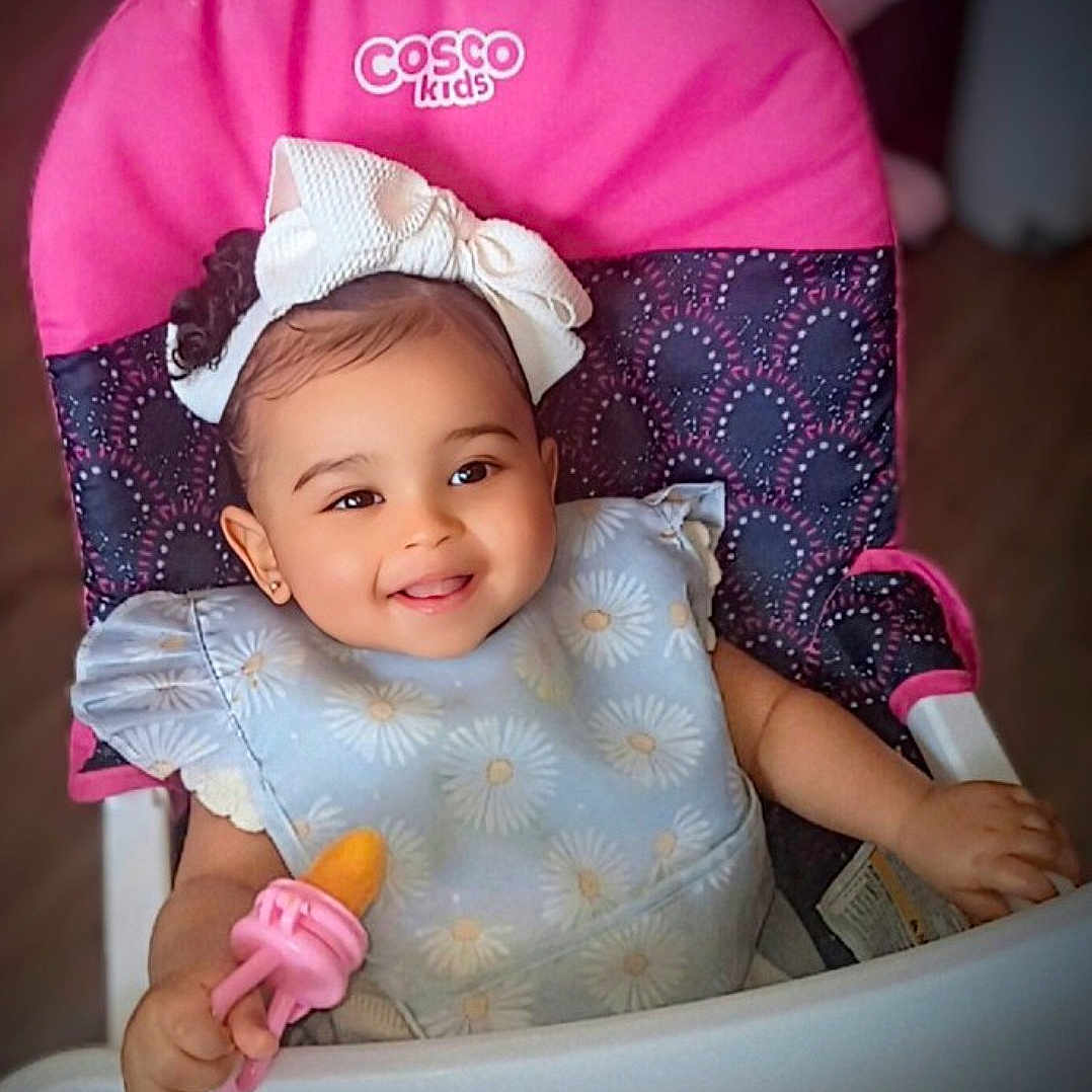 Monroe'Blu joined the competition — help win amazing prizes! baby, bib, bow, child, cute, daisy_pattern, face, feeding, happy, headband, high_chair, holding, indoor, infant, person, pink, portrait, smiling, toy, white