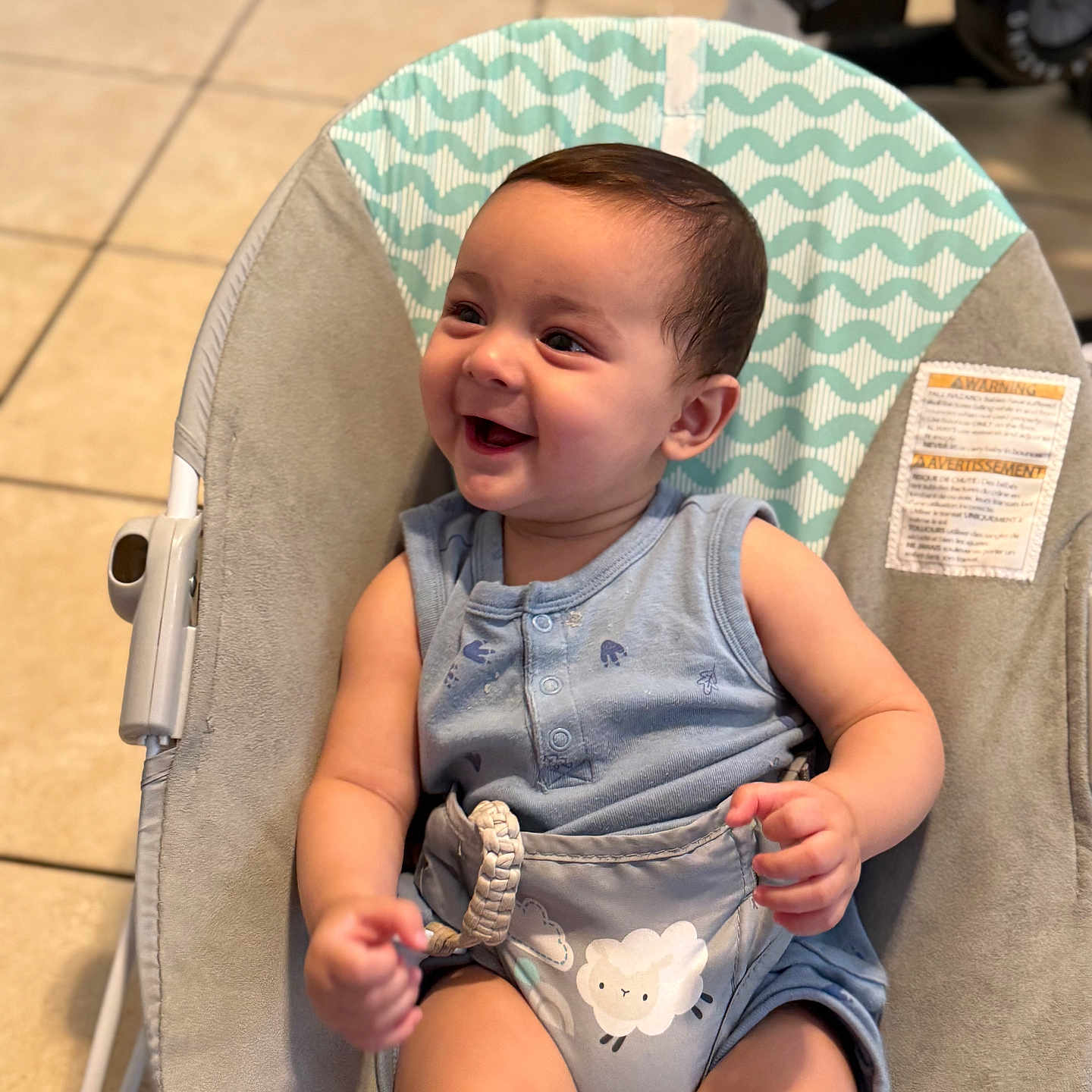 Santiago joined the competition — help win amazing prizes! baby, baby_chair, child, clothing, cute, floor, happy, happy_face, indoor, infant, onesie, pattern, person, playful, seat, sitting, small_child, smiling, tile_floor, young_child