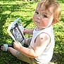 Timothy is registered to the contest to win money with this photo: toddler, child, grass, outdoor, sunlight, photo, baby_picture, white_tank_top, shorts, sandals, tree, shadow, greenery, skin_mark, holding, sitting, curious, portrait, daylight, nature