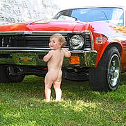 Timothy joined the competition — help win amazing prizes! toddler, child, naked, grass, car, vintage_car, orange_car, chevrolet, front_bumper, outdoor, daylight, greenery, curious, baby, vehicle, wheel, head, face, side_view, classic_car