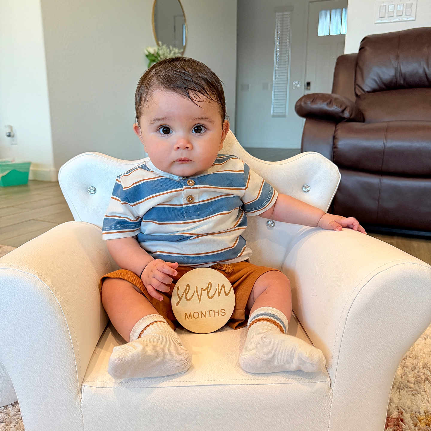Aavyan Sapkota joined the competition — help win amazing prizes! armchair, baby, brown_shorts, carpet, child, cute, flooring, flowers, indoor, infant, leather_sofa, living_room, mirror, person, portrait, seven_months, socks, striped_shirt, white_chair, wooden_sign