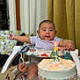 baby, infant, birthday_cake, candle, 4_months, high_chair, toy, celebration, milestone, sprinkles, colorful, indoor, curtain, table, smiling, person, clothing, cute, happy, child