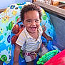 child, clothing, colorful, curly_hair, eyes, face, fun, hand, happy, indoor, inflatable, mouth, plastic, playful, seat, shorts, smiling, striped_shirt, toddler, toy