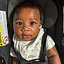 baby, child, car_seat, infant, face, straps, onesie, seatbelt, sitting, looking, curious, indoors, closeup, head_support, safety, cute, person, young, skin, expression