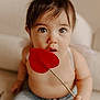 Lorenzo joined the competition — help win amazing prizes! baby, child, heart, red, felt, stick, curious, wide_eyes, couch, beige, soft, indoor, portrait, cute, infant, skin, young, person, seated, closeup