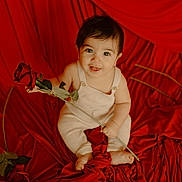 Lorenzo is registered to the contest to win money with this photo: baby, child, rose, red, flower, smile, cute, portrait, infant, fabric, sitting, cute_face, holding, love, valentine, happy, small, one_person, indoors, skin