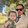 baby, adult, man, child, outdoor, tree, sunglasses, hat, dress, green, nature, sunlight, grass, park, person, holding, portrait, daytime, leafy, casual